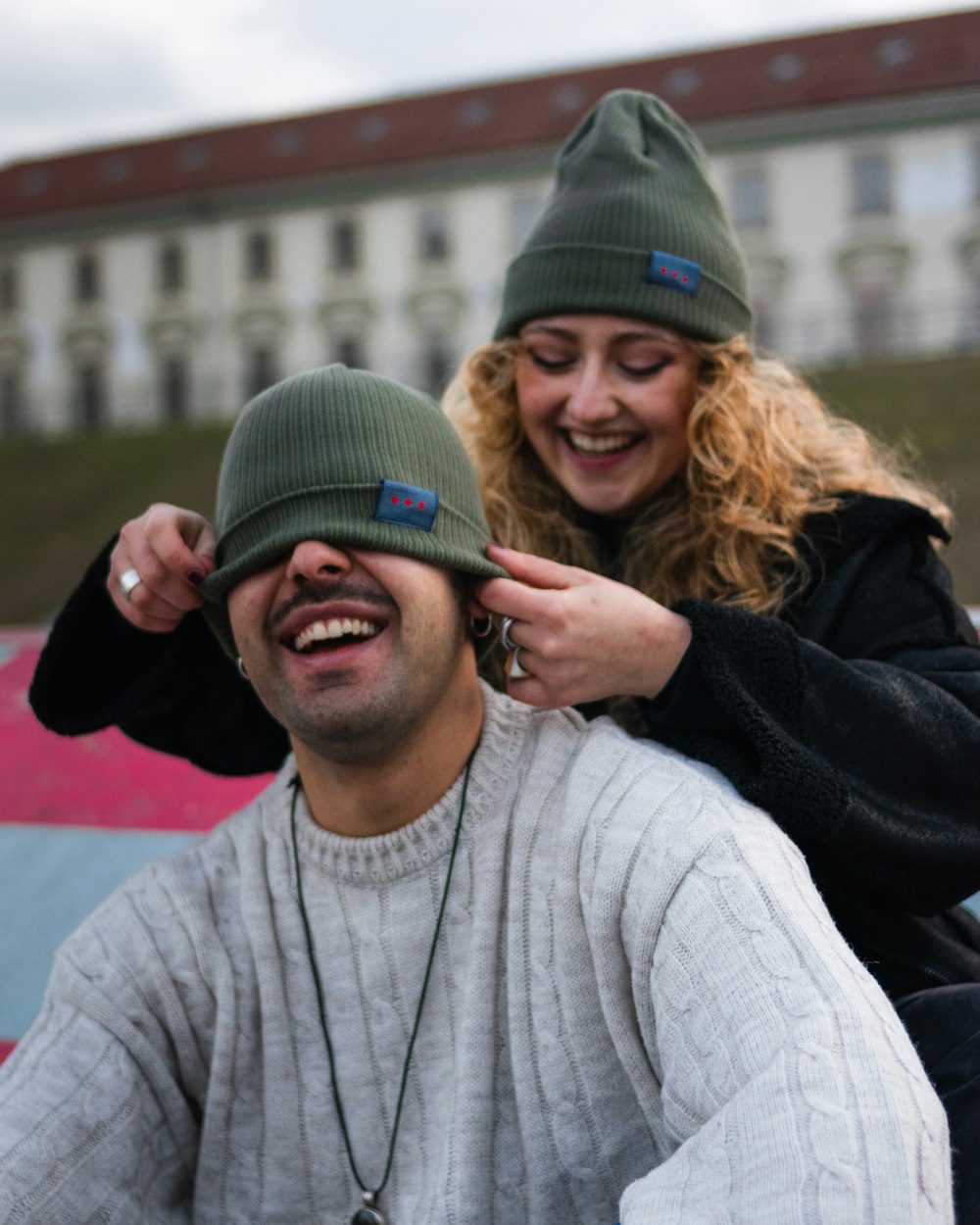 man in gray sweater beside woman in black knit cap