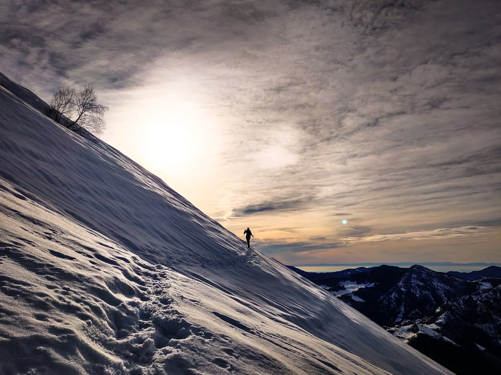 person standing on snow covered mountain during sunset