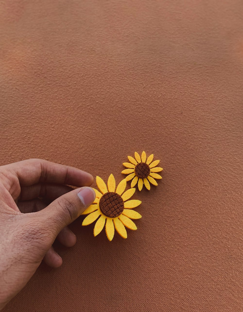 Person holding sunflower toys on a brown background