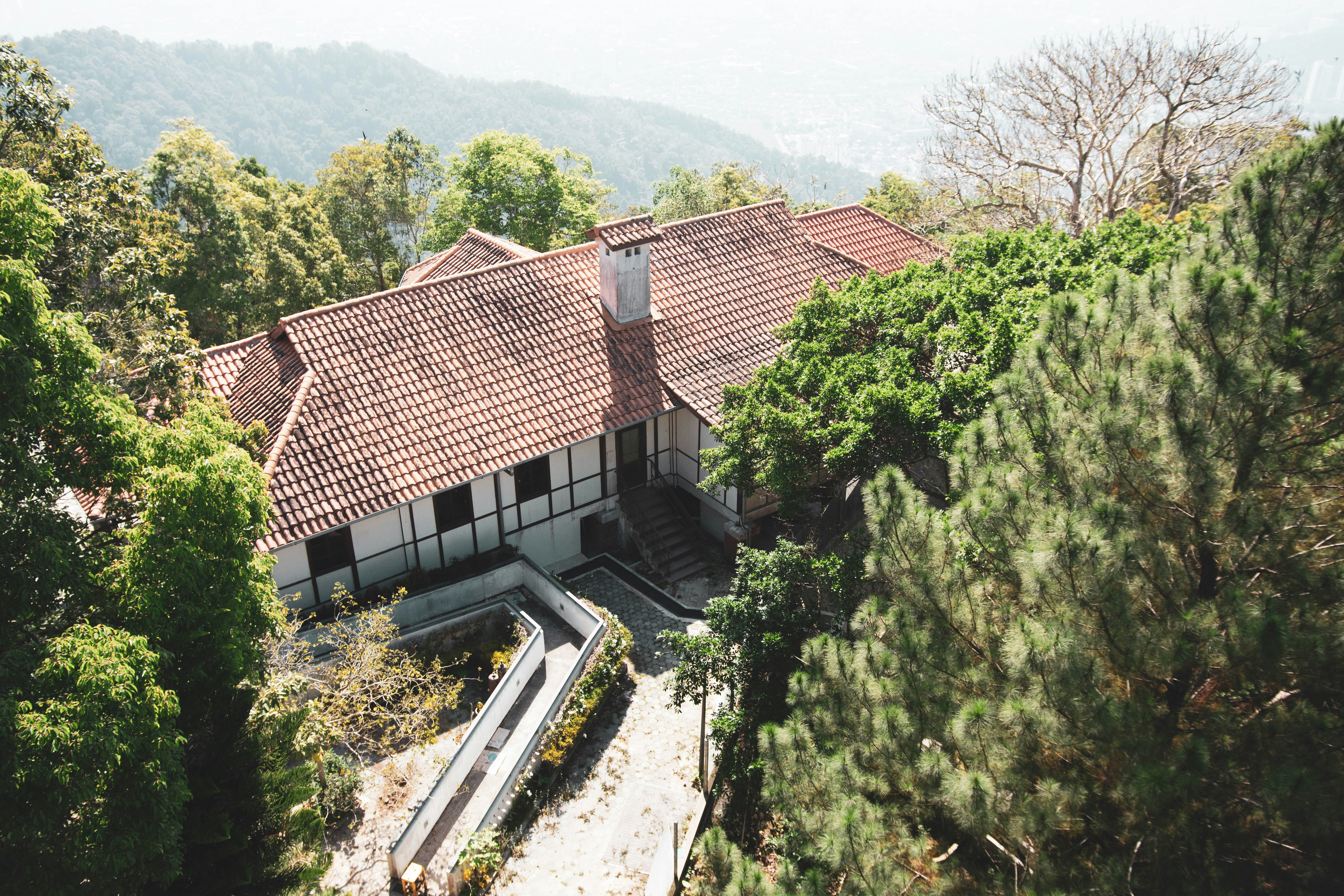 Brown and white concrete house near green trees during daytime photo ...