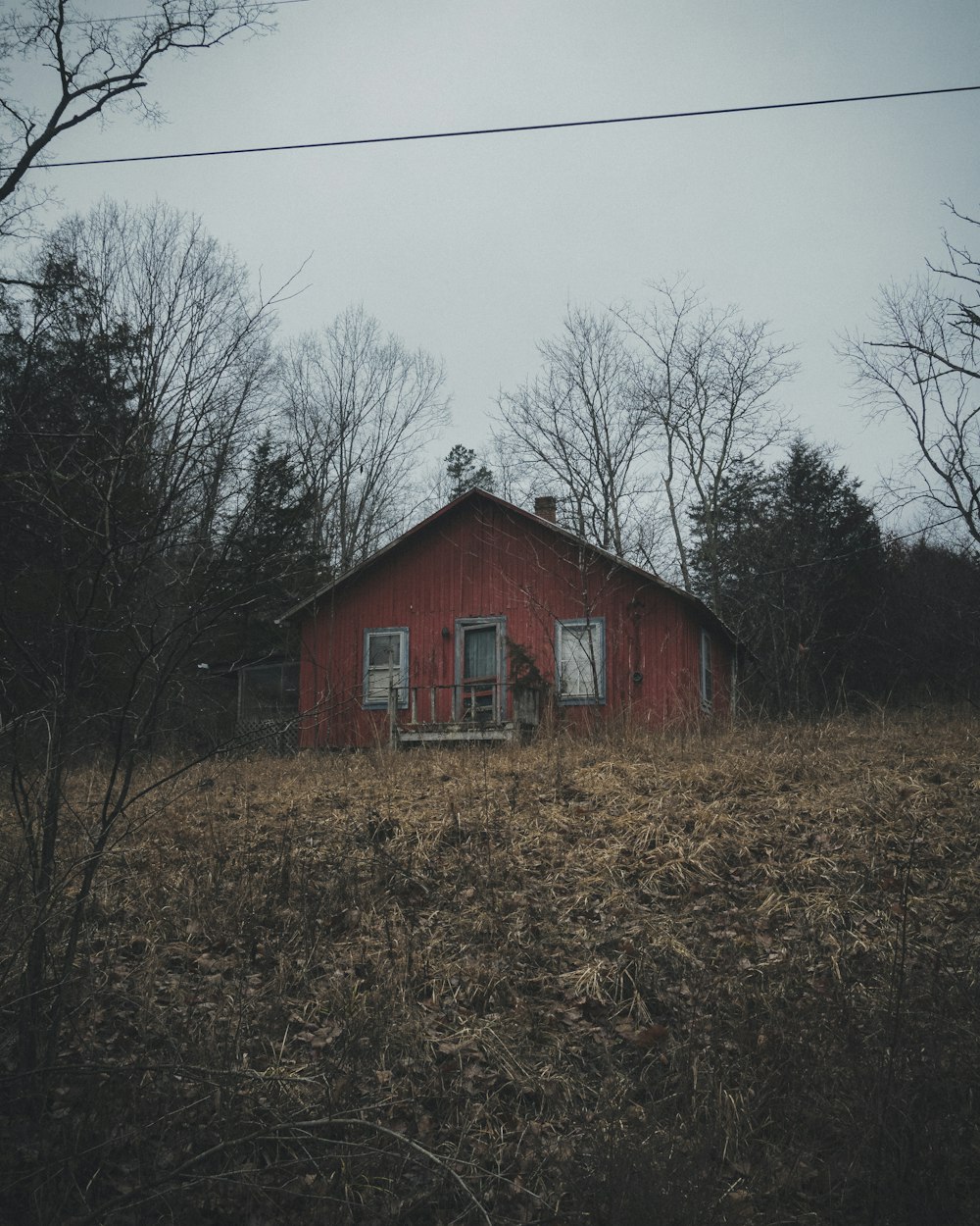 brown wooden house near bare trees under gray sky