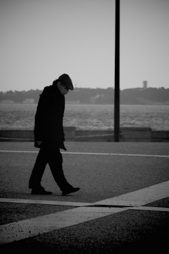 man in black coat standing on sidewalk during daytime