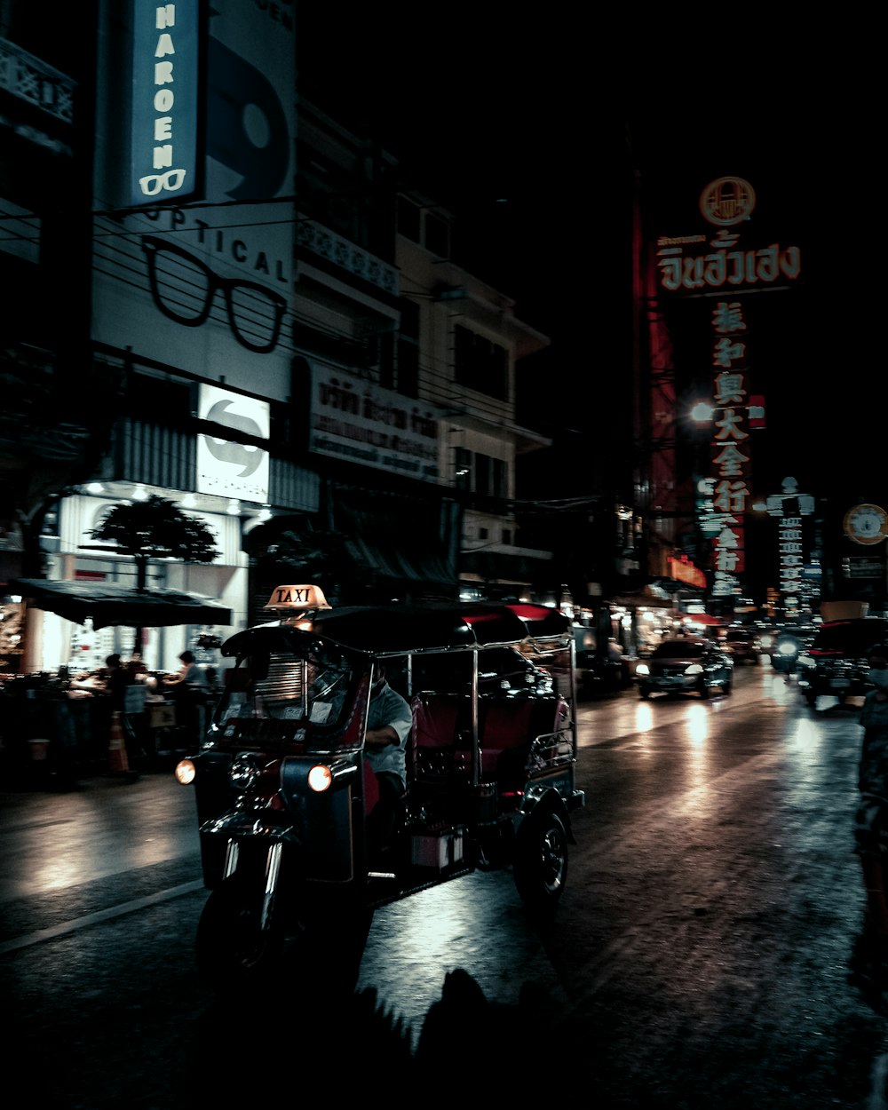 夜間に赤と黒のオートリクシャーに乗って道路を走る人々