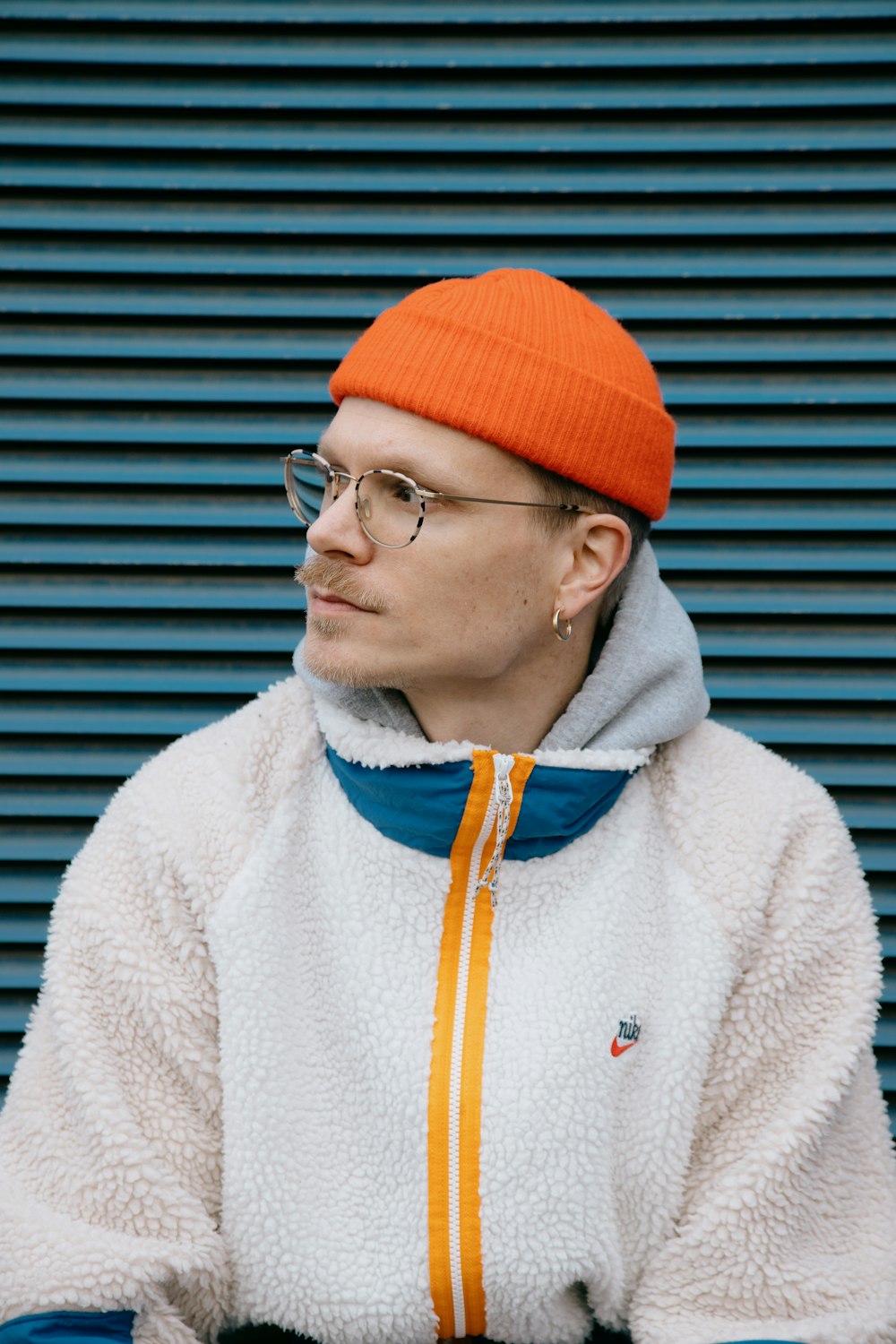 man in white zip up jacket wearing orange knit cap and eyeglasses