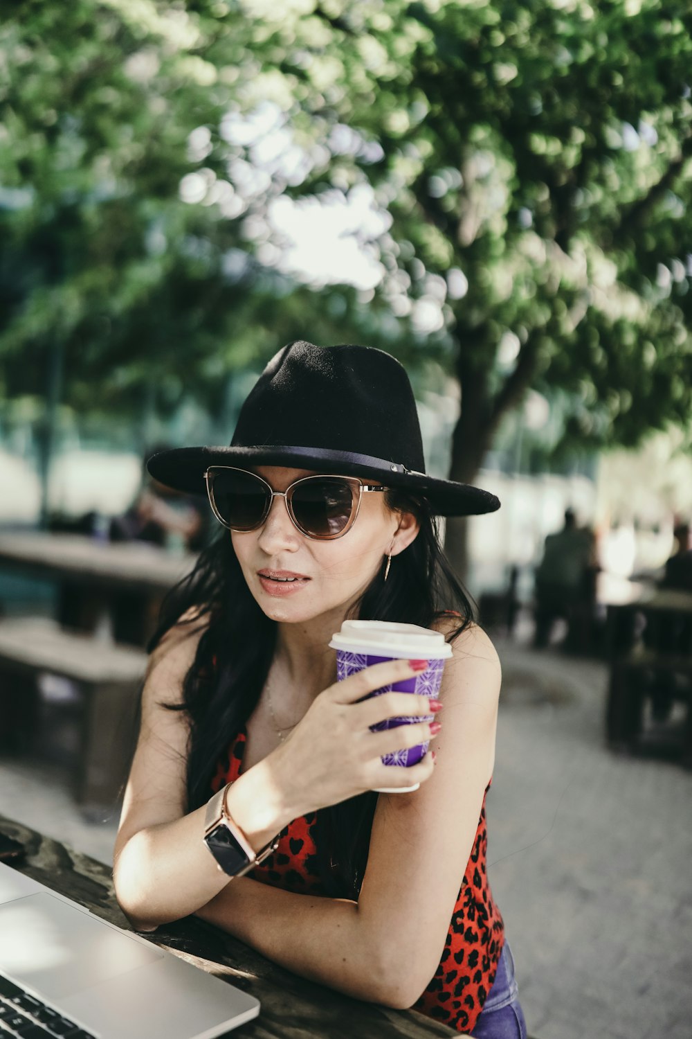 woman in black hat holding white and blue cup
