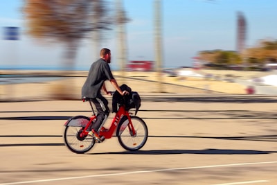 man in black jacket riding red motorcycle on road during daytime