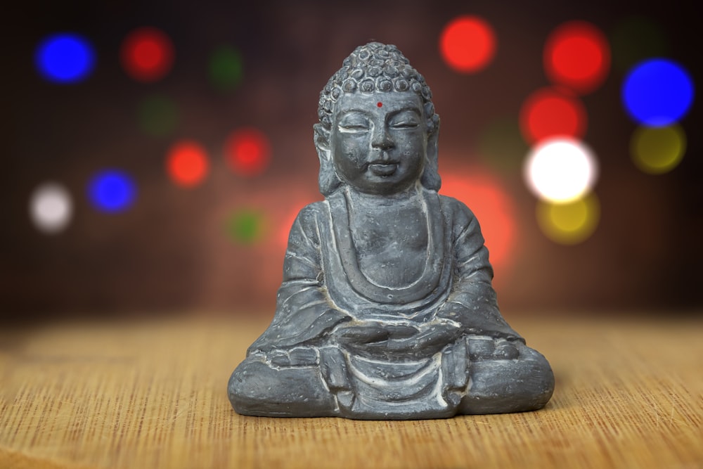 Figura de Buda de cerámica gris sobre mesa de madera marrón