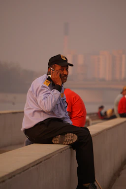 A professional maintenance worker in uniform talking on the phone near a modern building.