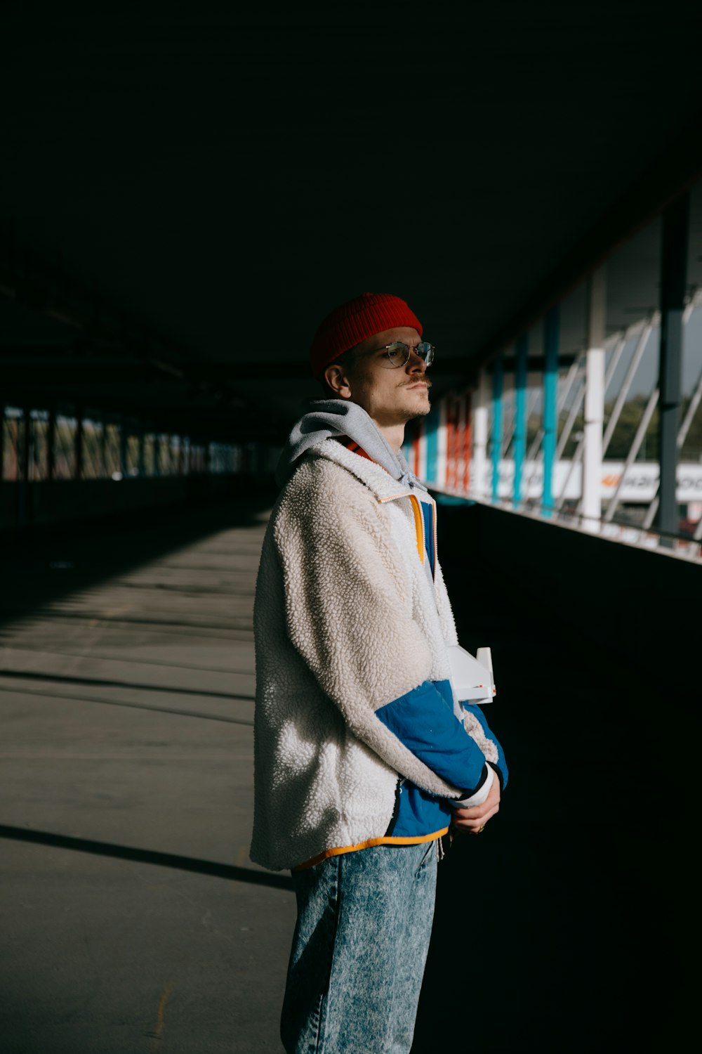 man in red knit cap and gray jacket standing on bridge during daytime