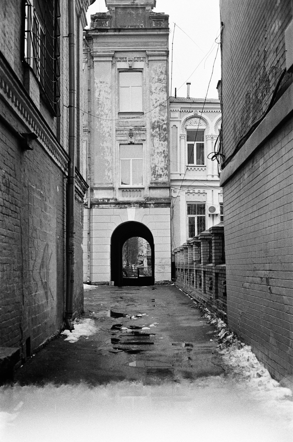 grayscale photo of hallway with brick walls