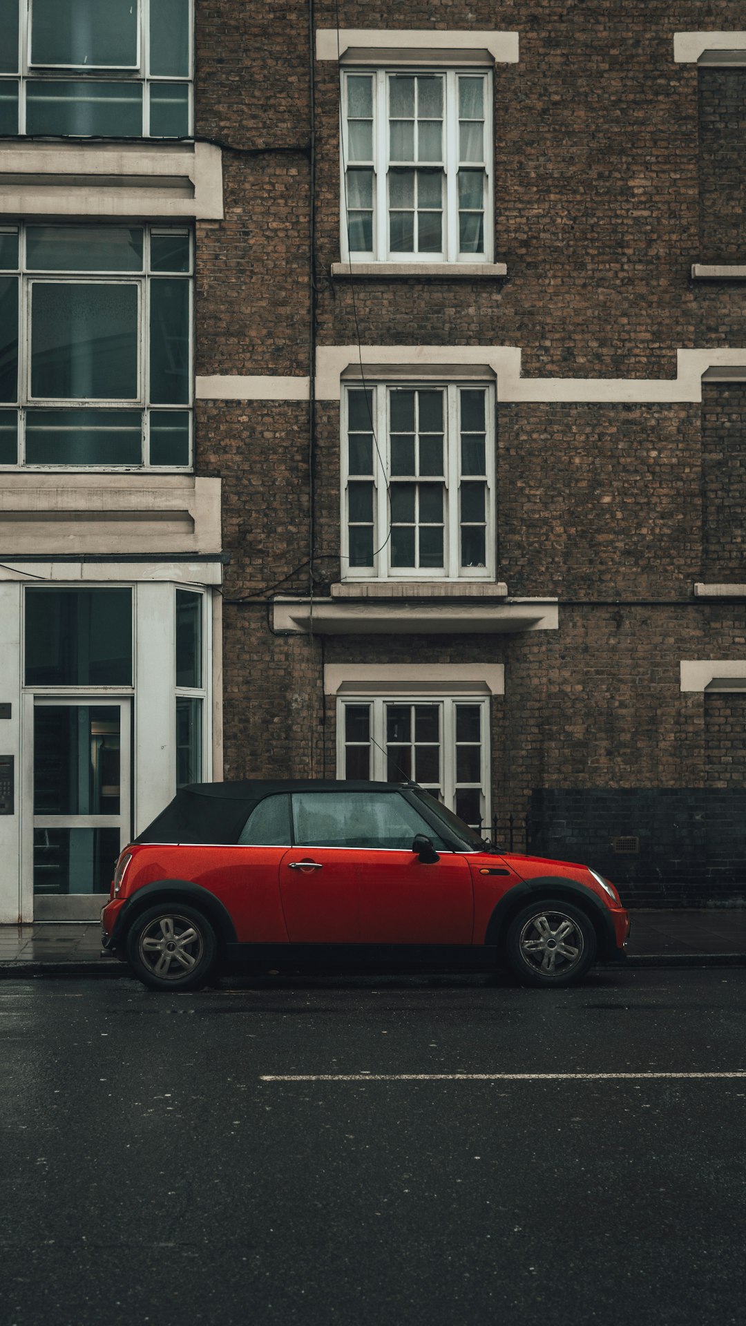 red car parked beside brown brick building