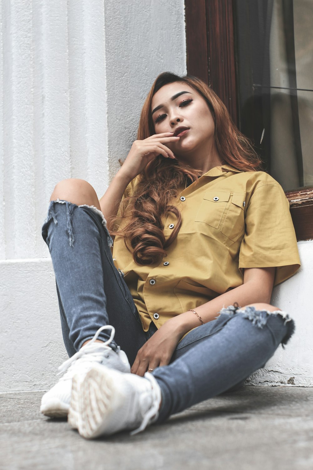 a woman sitting on the ground next to a window