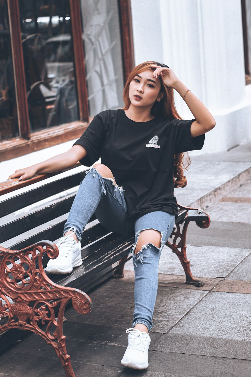 woman in black crew neck t-shirt and blue denim jeans sitting on brown wooden bench