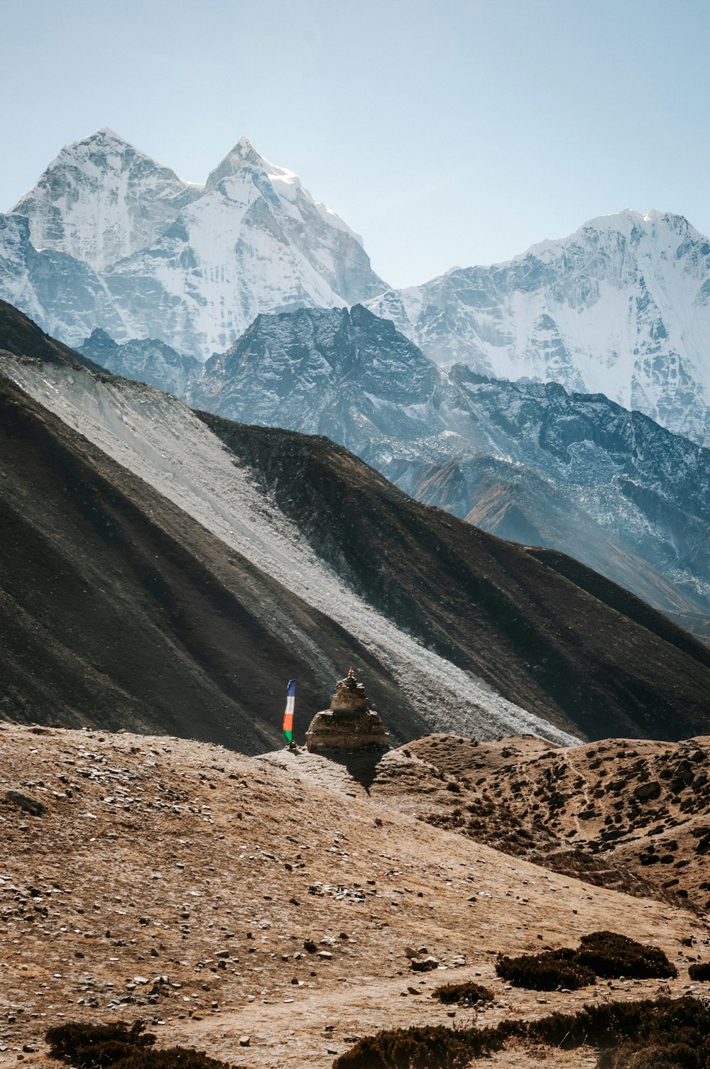 Persona in giacca arancione in piedi sulla montagna rocciosa marrone durante il giorno