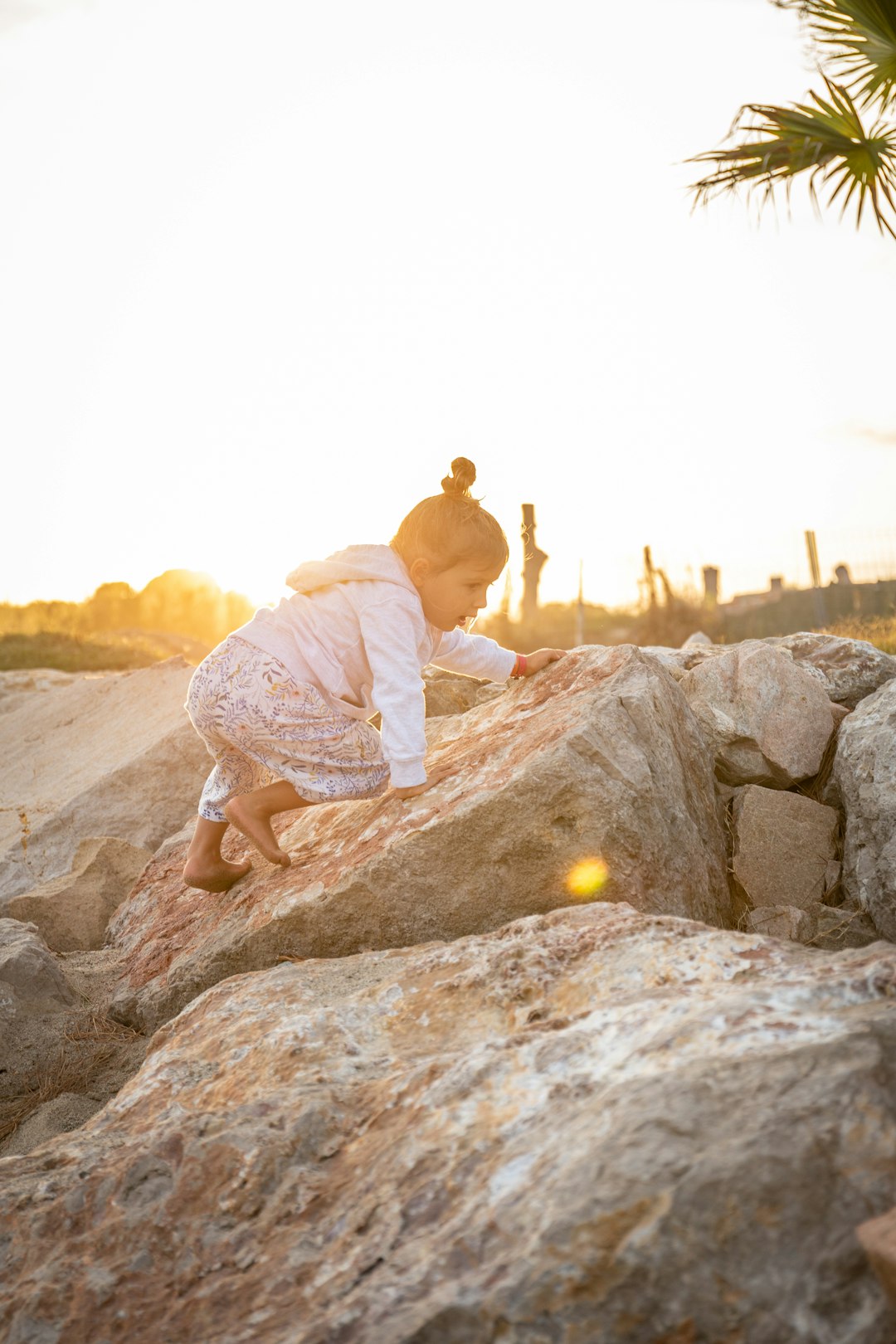 man in white shirt and brown shorts sitting on rock during daytime