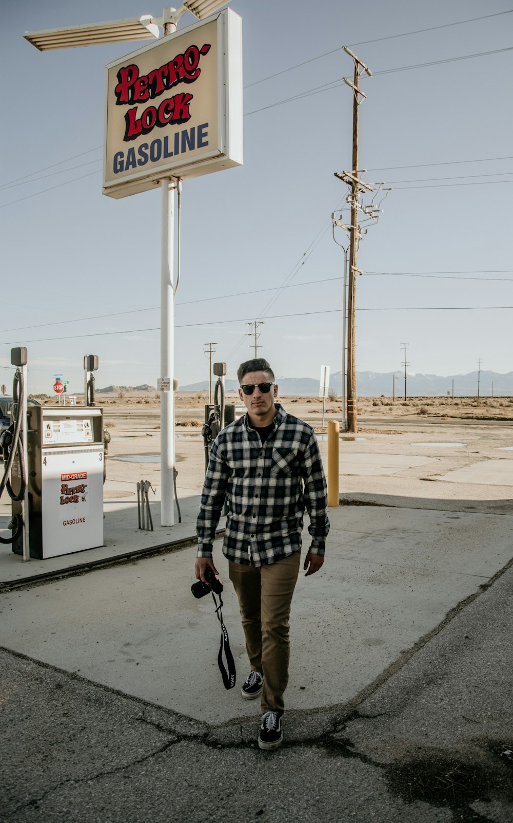 man in black and white checkered button up shirt and brown shorts standing on sidewalk during