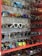 A collection of various sunglasses displayed on multiple glass shelves, featuring a range of colors and styles. The frames vary from modern and sleek to retro and bold designs, with lenses that are tinted in different hues such as blue, gold, and dark shades.