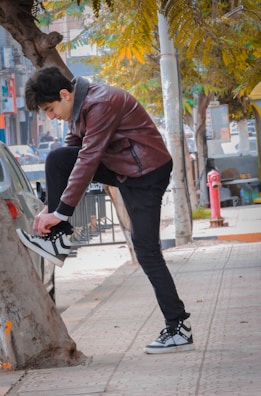 Woman tying shoelaces, wearing sporty leggings and a light jacket, in an urban park.