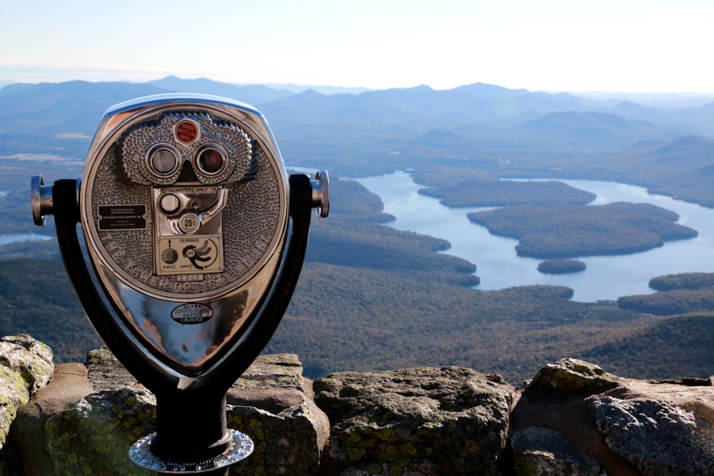 Telescopio operado con monedas negras y grises en la cima de la montaña durante el día