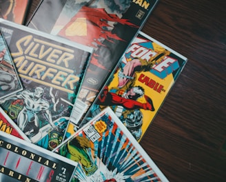 a pile of comics sitting on top of a wooden table