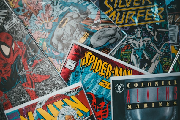 An assortment of comic book covers featuring iconic characters like Spider-Man and Batman. The covers showcase vibrant colors and dynamic artwork, with titles prominently displayed.