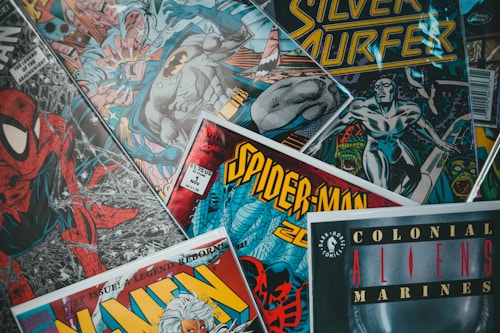 An assortment of comic book covers featuring iconic characters like Spider-Man and Batman. The covers showcase vibrant colors and dynamic artwork, with titles prominently displayed.