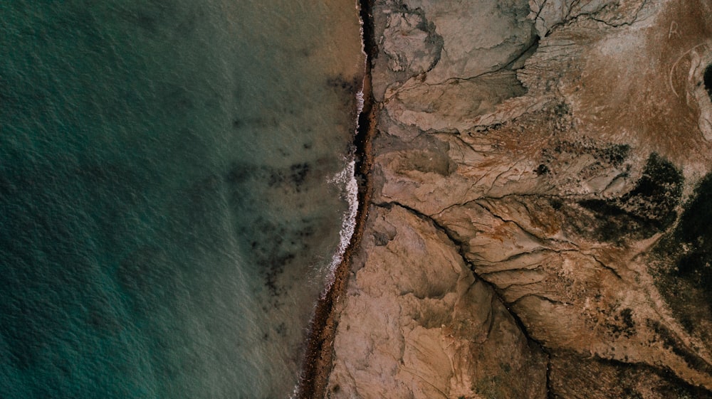 brown rocky mountain beside body of water during daytime