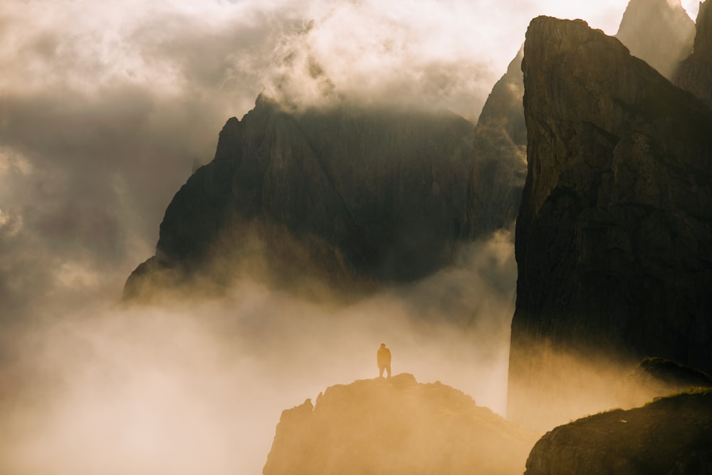 person standing on rock formation during foggy day