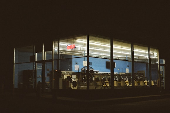 A cozy laundromat facade with washing machines visible through large windows.