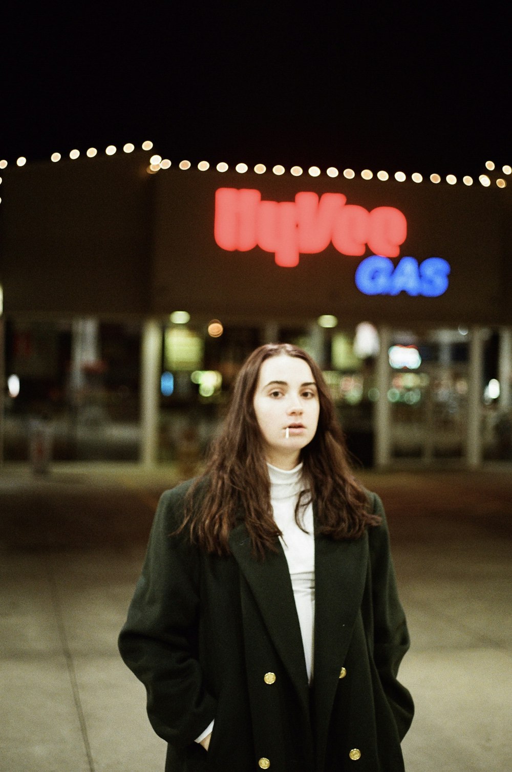 woman in black coat standing near red and white love neon light signage