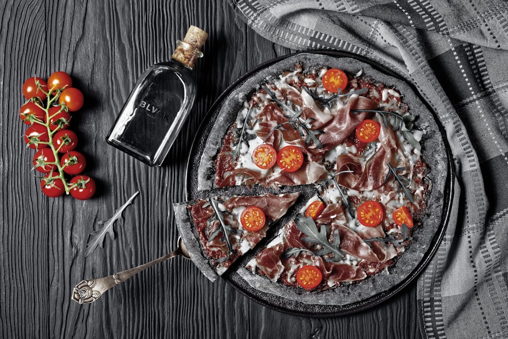 pizza on round black ceramic plate beside silver fork and knife