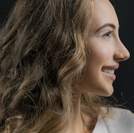 Side profile of woman smiling with long, voluminous hair extensions cascading over her shoulders.