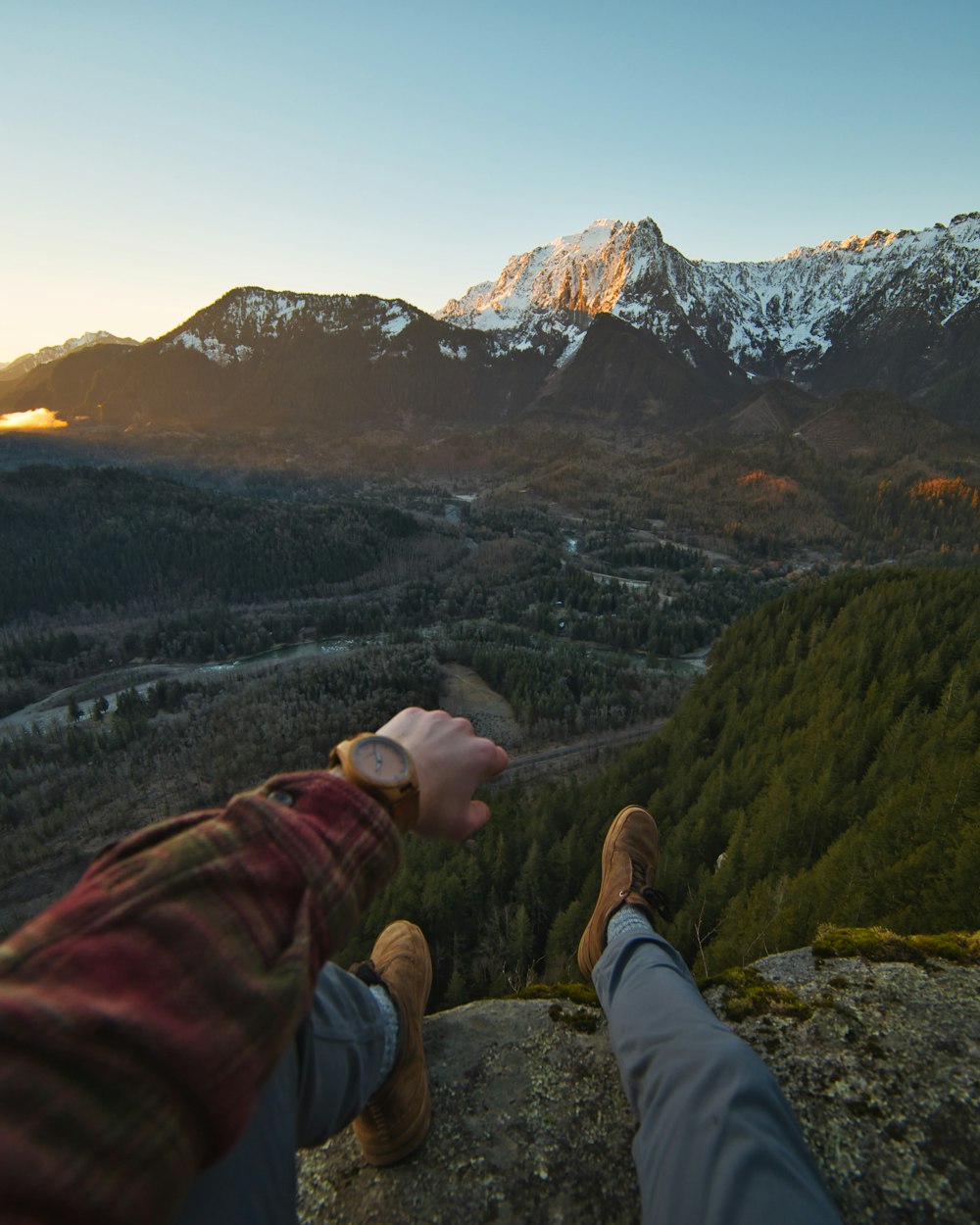 person in red and brown jacket sitting on rock formation during daytime