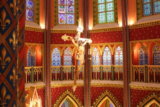 An elegant church interior bathed in warm gold and deep red light, featuring traditional Syriac crosses and motifs.
