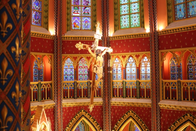 An elegant church interior bathed in warm gold and deep red light, featuring traditional Syriac crosses and motifs.