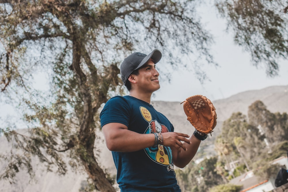 man in blue crew neck t-shirt holding brown round pastry during daytime