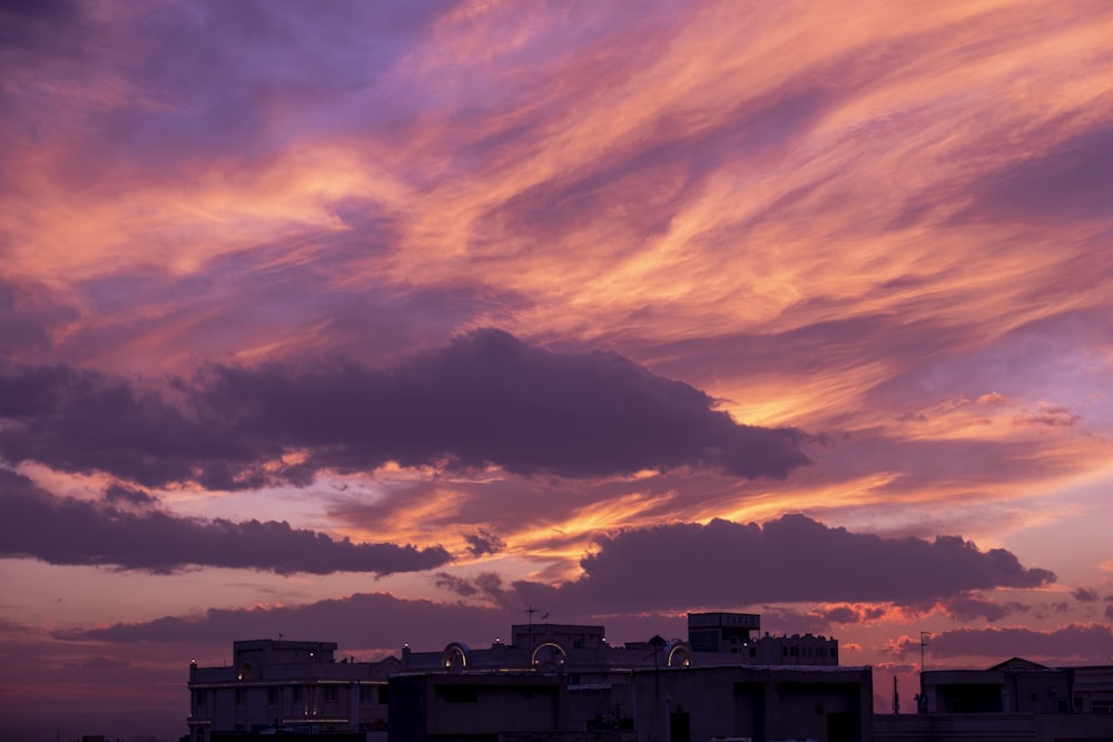 Weißes Betongebäude unter bewölktem Himmel bei Sonnenuntergang