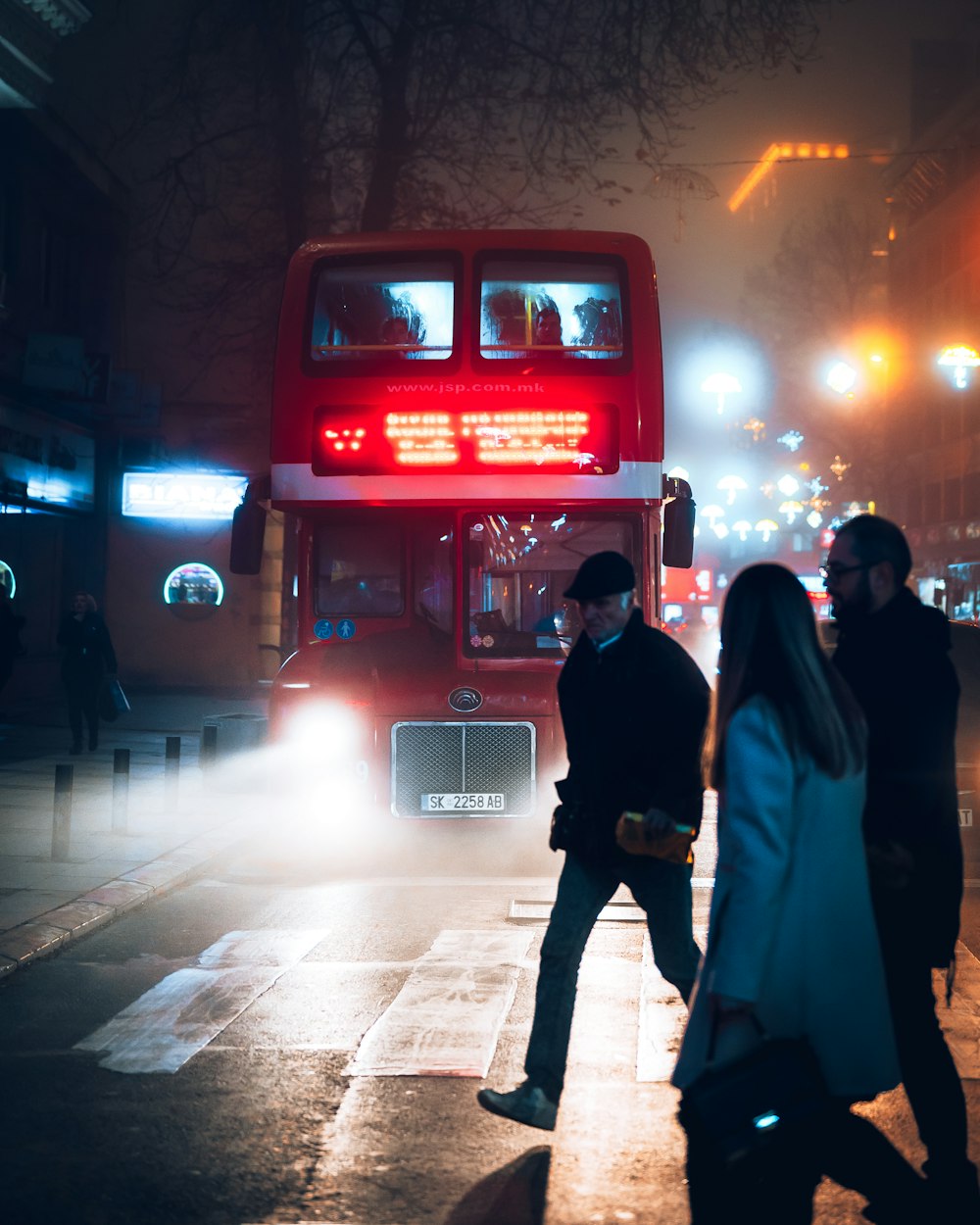 woman in black coat standing beside red telephone booth during night time