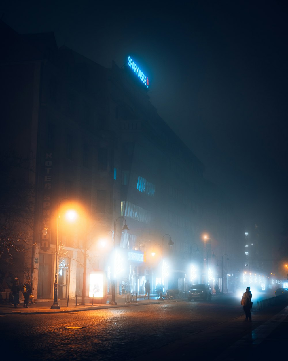 man in black jacket walking on sidewalk during night time