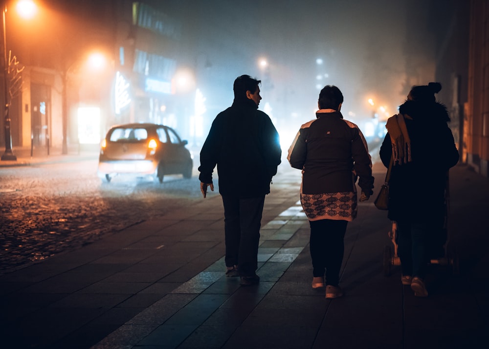 people walking on sidewalk during night time