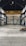 An empty industrial warehouse with high ceilings and large metal beams. The space is spacious with concrete floors and walls that show signs of wear, offering a gritty and raw aesthetic. Overhead, a big yellow crane is installed, indicating the space's potential for lifting heavy materials.