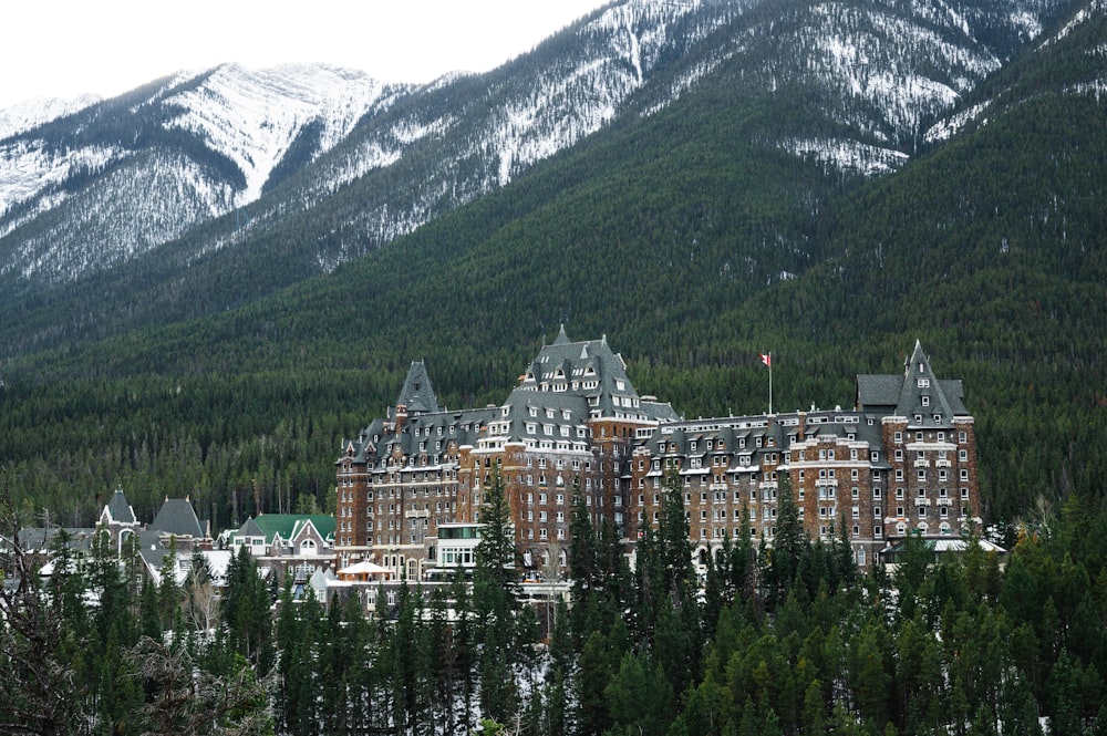 white and brown concrete buildings near green trees and mountain during daytime