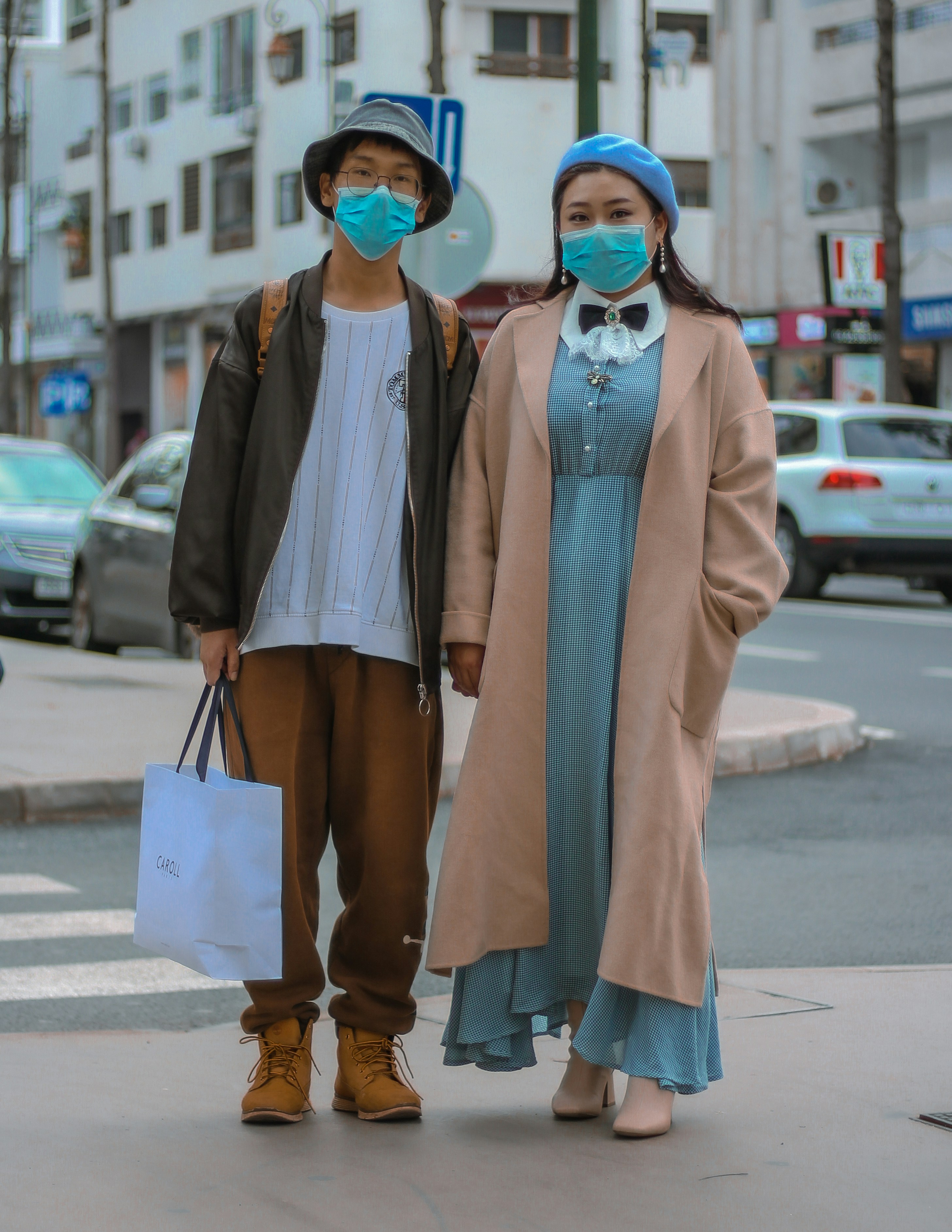 woman in blue dress and white cardigan holding white paper bag