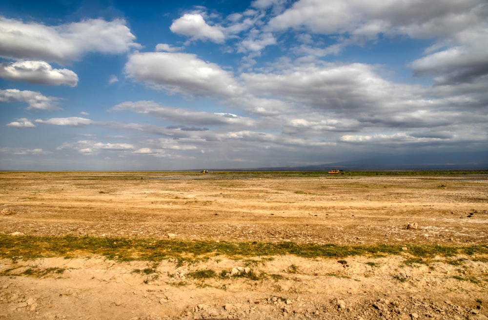 brown field under white clouds and blue sky during daytime