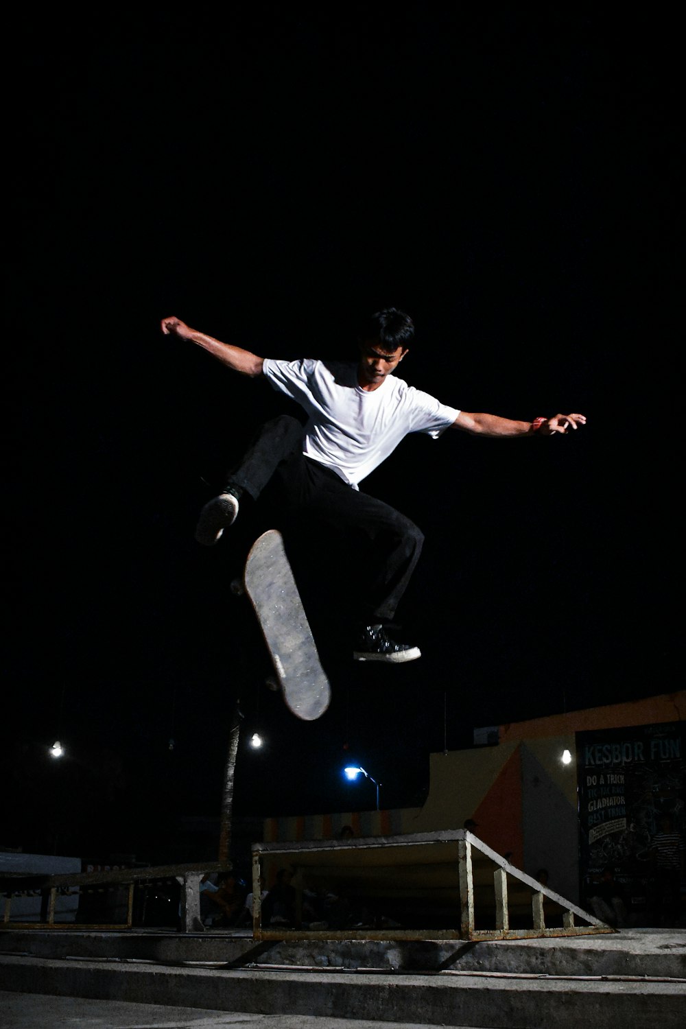 man in white t-shirt and black pants sitting on white plastic chair during nighttime