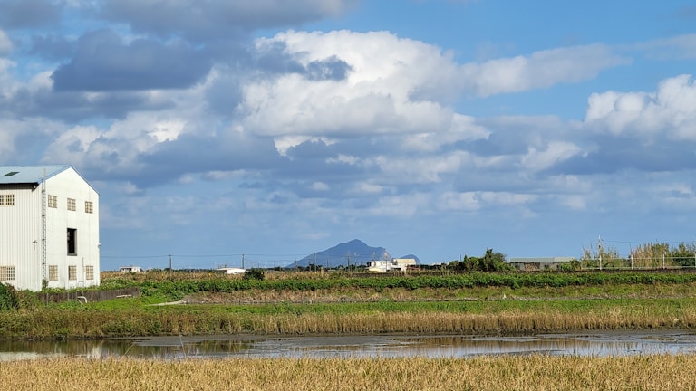 A scenic view of rolling farmland with a modern manufacturing facility blending into the landscape.
