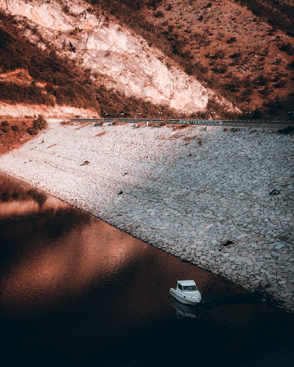 white boat on gray sand near brown mountain during daytime