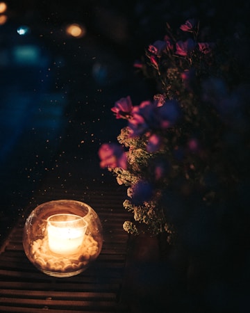 A single lit candle in a clear glass holder, representing a quiet remembrance for Barbara Edwards
