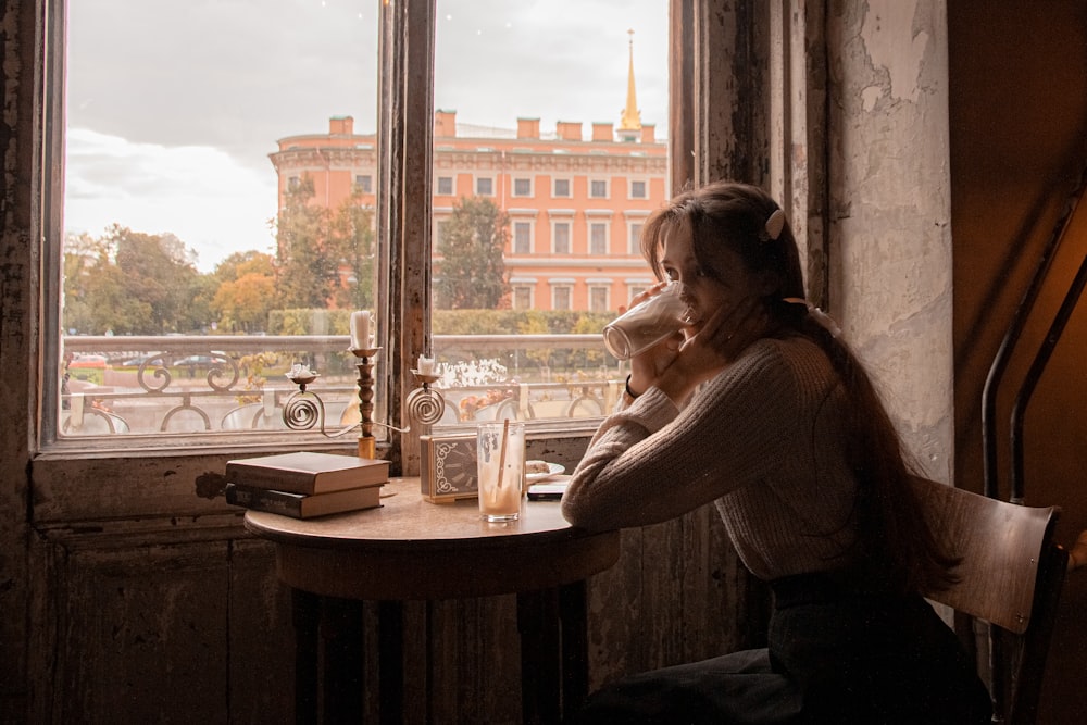 woman in black long sleeve shirt sitting beside window during daytime