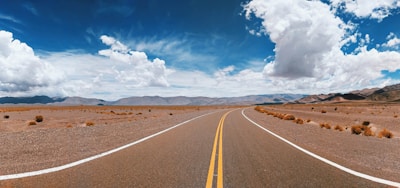 A winding desert road stretching beneath a vast blue sky.